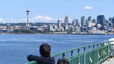 kids looking across the bay at the space needle from the deck of a ferry