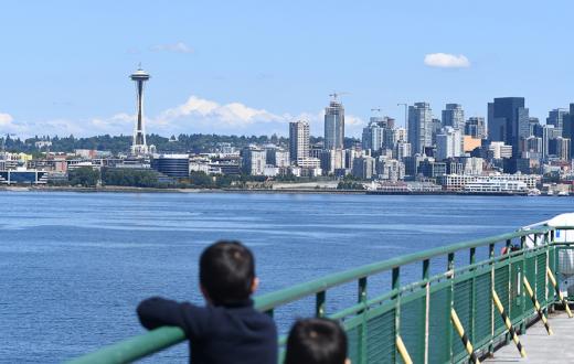 kids looking across the bay at the space needle from the deck of a ferry