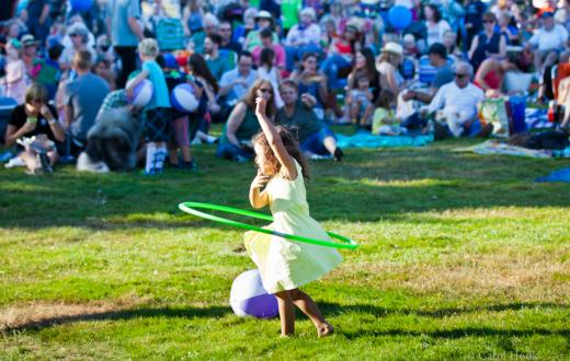 Girl plays with hula hoop at a Celebrate Woodinville summer concert, free outdoor performance for Seattle-area families