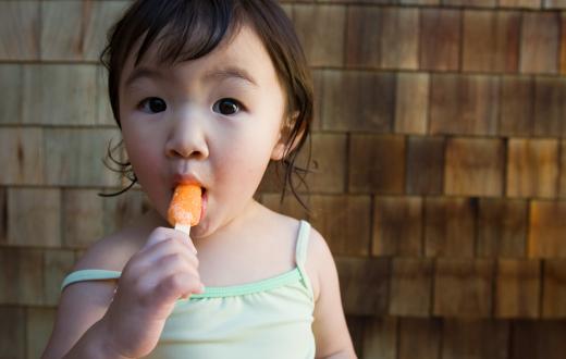Girl eating popsicle after playing indoors when it's too hot to play inside