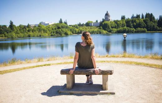 Woman sitting on a park bench relaxing and looking at water