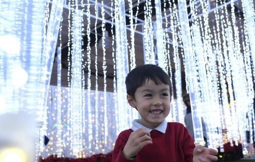 little boy smiling with glittering lights behind him