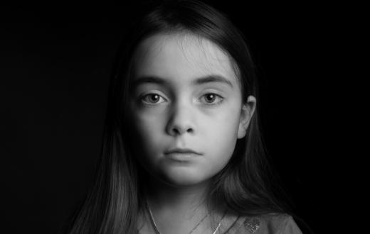 black and white photo of a serious girl partially in shadow looking at the camera