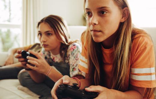 Two girls playing video games on a couch