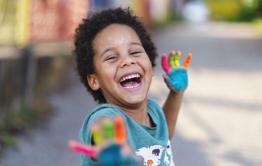 happy little boy with rainbow paint on his palms