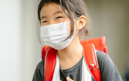 girl smiling under a face mask