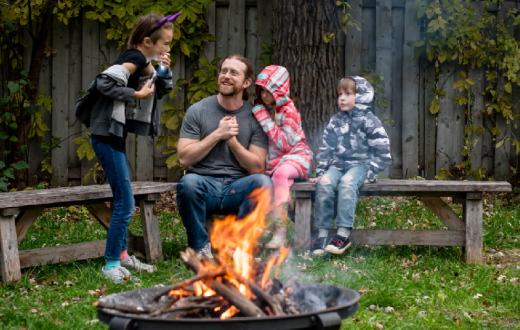 A father with 3 kids around a campfire