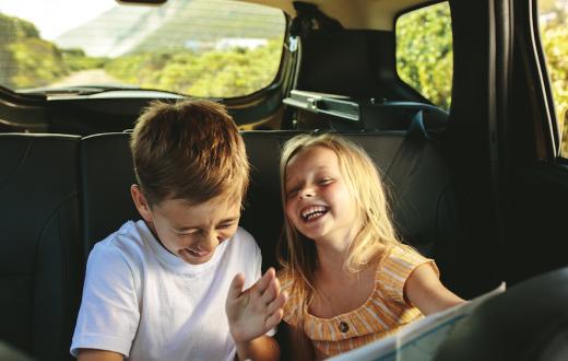 brother and sister giggling in the backseat of the car