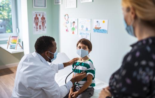 doctor listening to a child's heart with a stethoscope while the mom watches