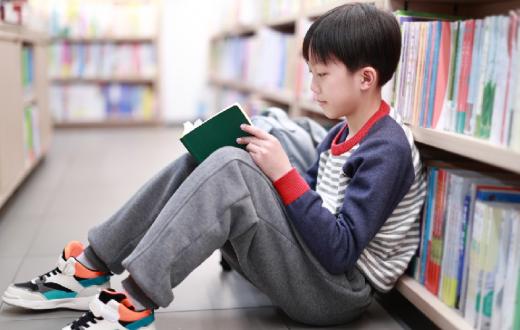 Kid-reading-book-in-library