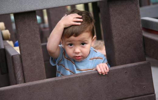 toddler holding his head on a play structure