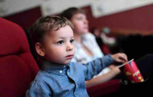 Toddler boy eating popcorn in a movie theater