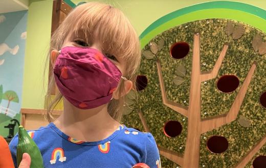 Happy young girl wearing a face covering at KidsQuest Children's Museum in Belleuve reopening after pandemic closure
