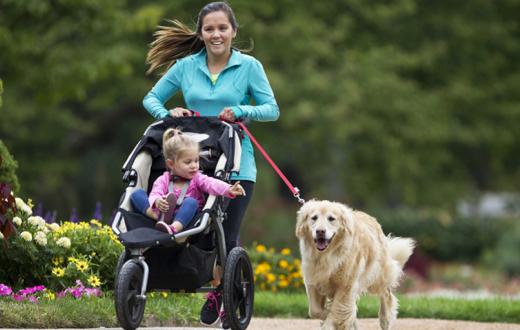 Mom pushing a stroller with a dog on a leash