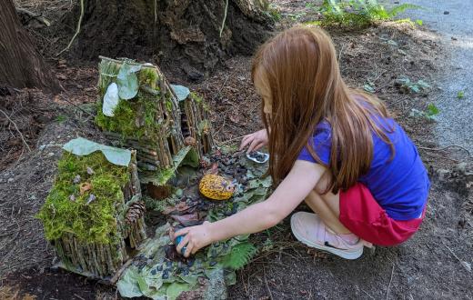 Young girl crouches next to a fairy house along the Pine Lake Fairy Trail in Sammamish, Wash., near Seattle, among fun free kids' activities for summer 2022